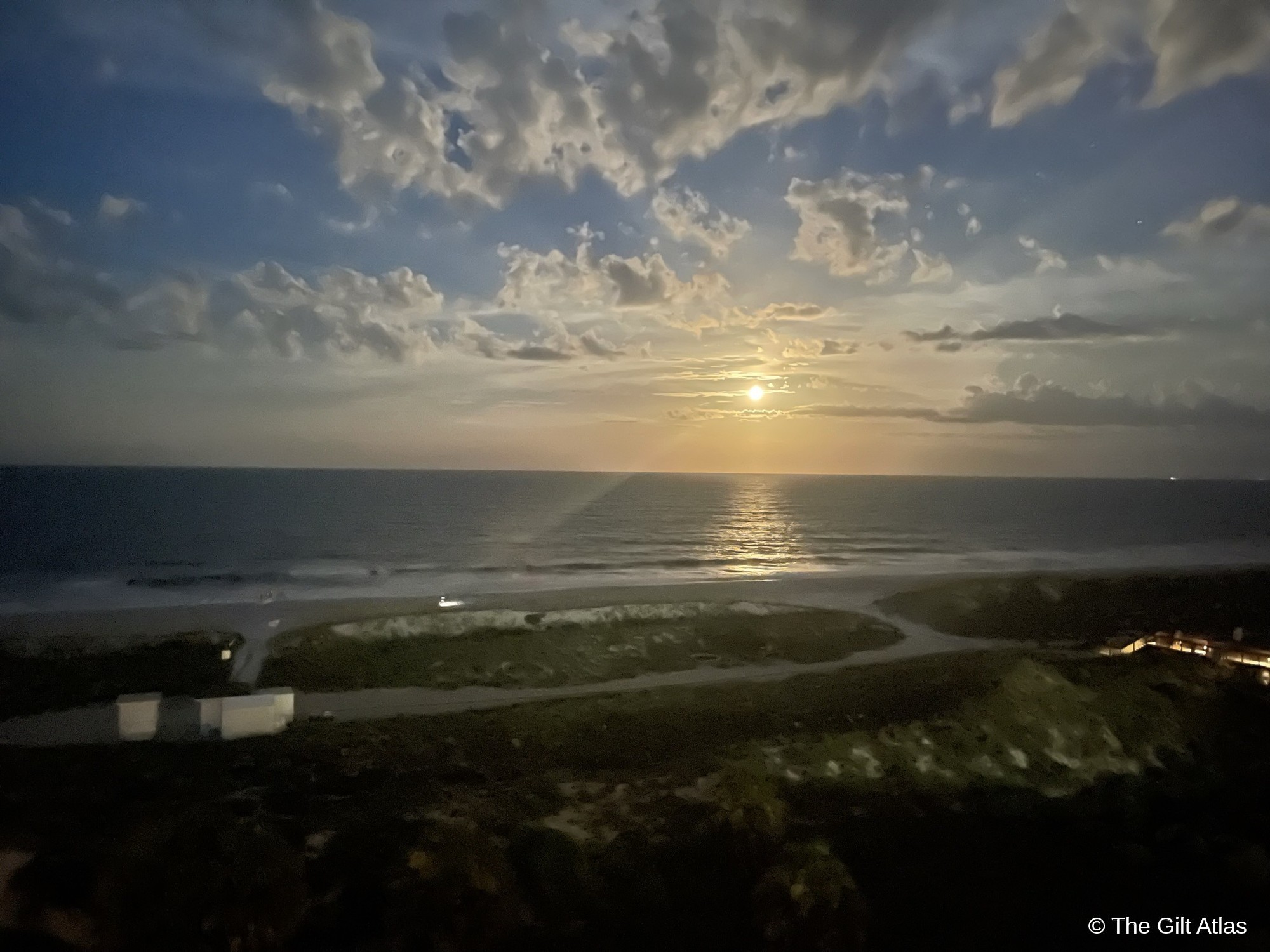 Moonrise over the Atlantic Ocean from the corner suite balcony at Ritz-Carlton Amelia Island — golden moonlight reflecting on the water, dramatic clouds, dune landscape below