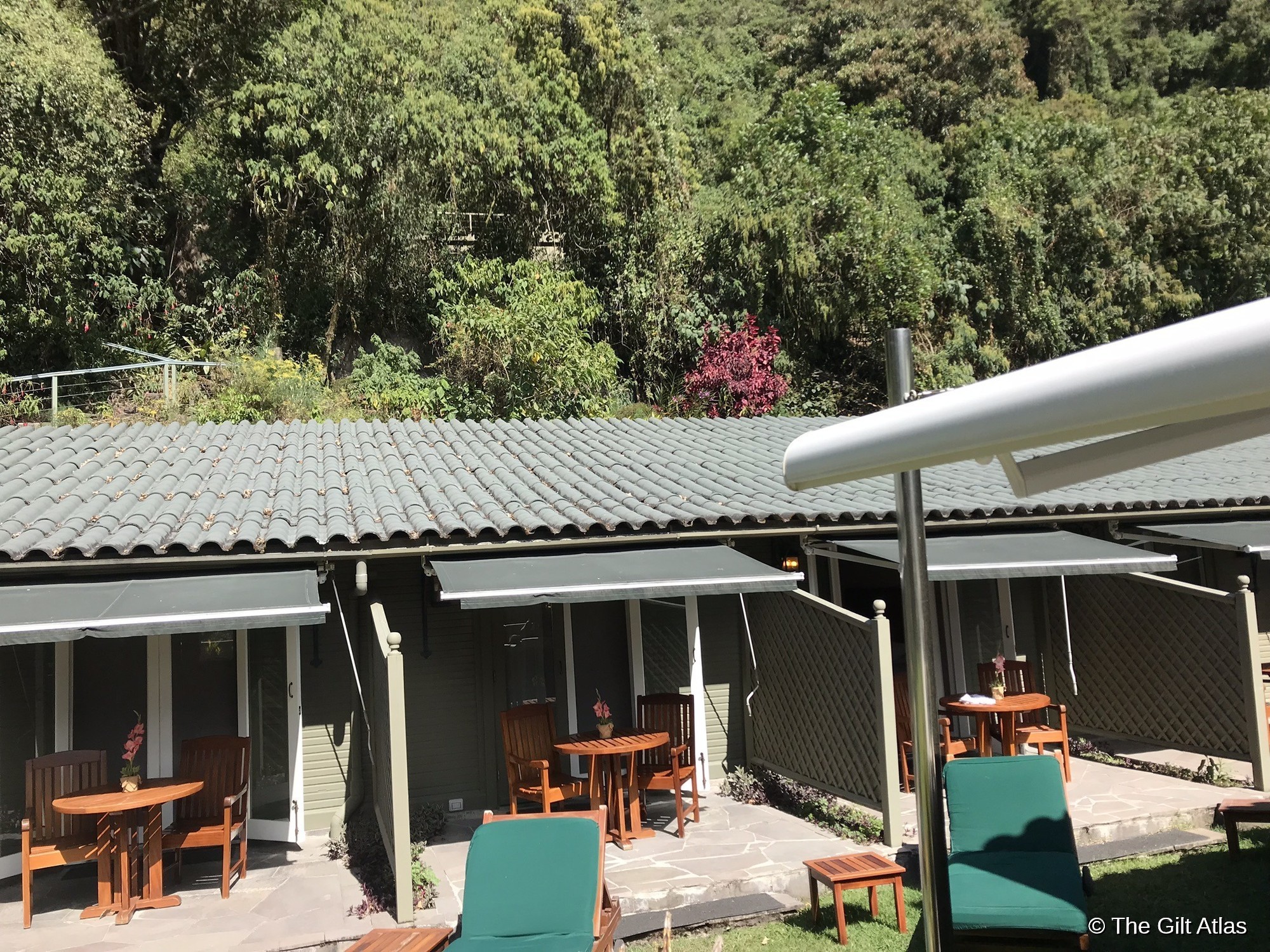 The Sanctuary Lodge's terrace and rooms, with awnings and outdoor seating set against the cloud forest