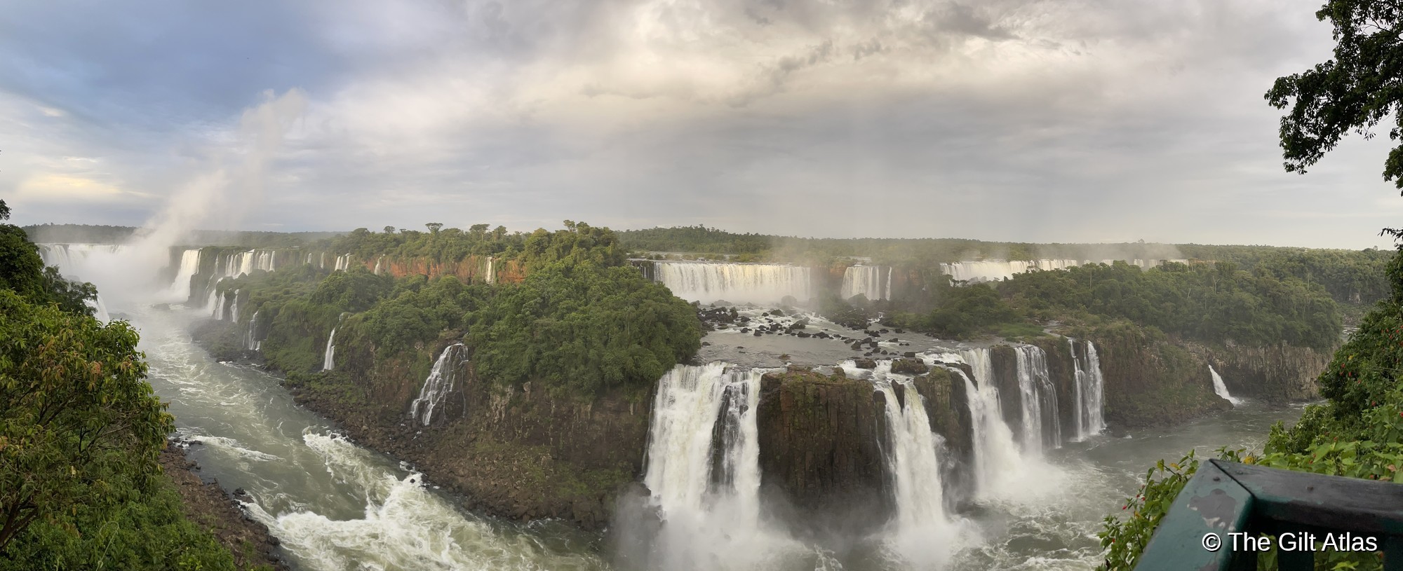 Panoramic view of Iguazu Falls from the Brazilian side — the full width of the falls visible with rainbow in the mist above