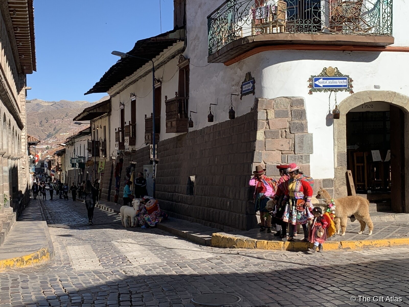 Cusco street scene on Santa Catalina Ancha with women in traditional Andean dress and llamas