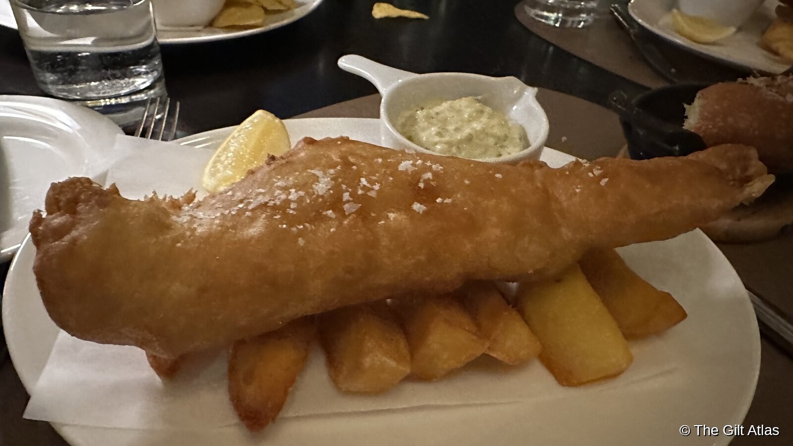 Classic British fish and chips — a generous battered fillet over chips with tartar sauce and a lemon wedge