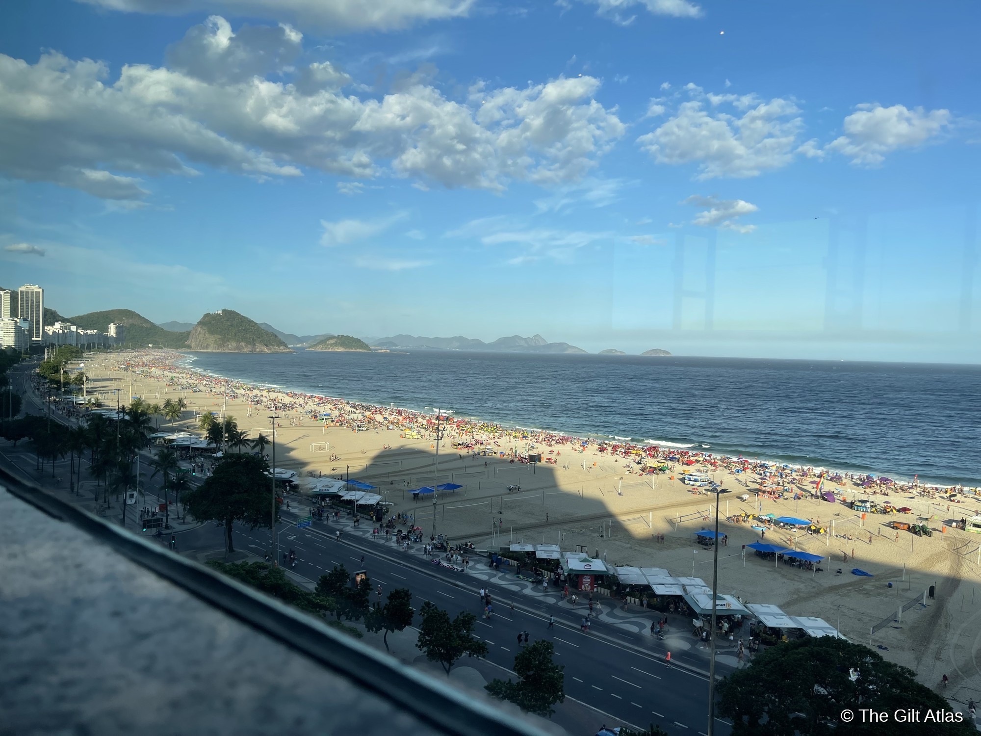 Copacabana Beach viewed from high floor of JW Marriott Rio de Janeiro — packed with colorful umbrellas, mountains and islands in the distance
