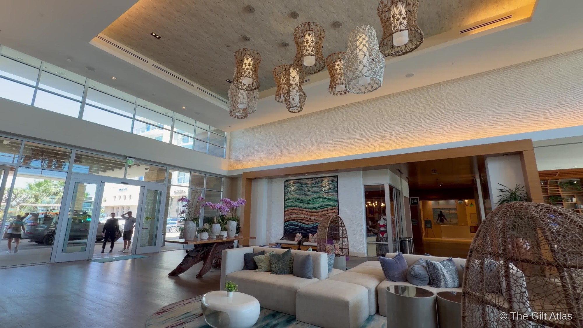 Pasea Hotel lobby — woven pendant lights, coastal artwork, and open seating area in warm afternoon light
