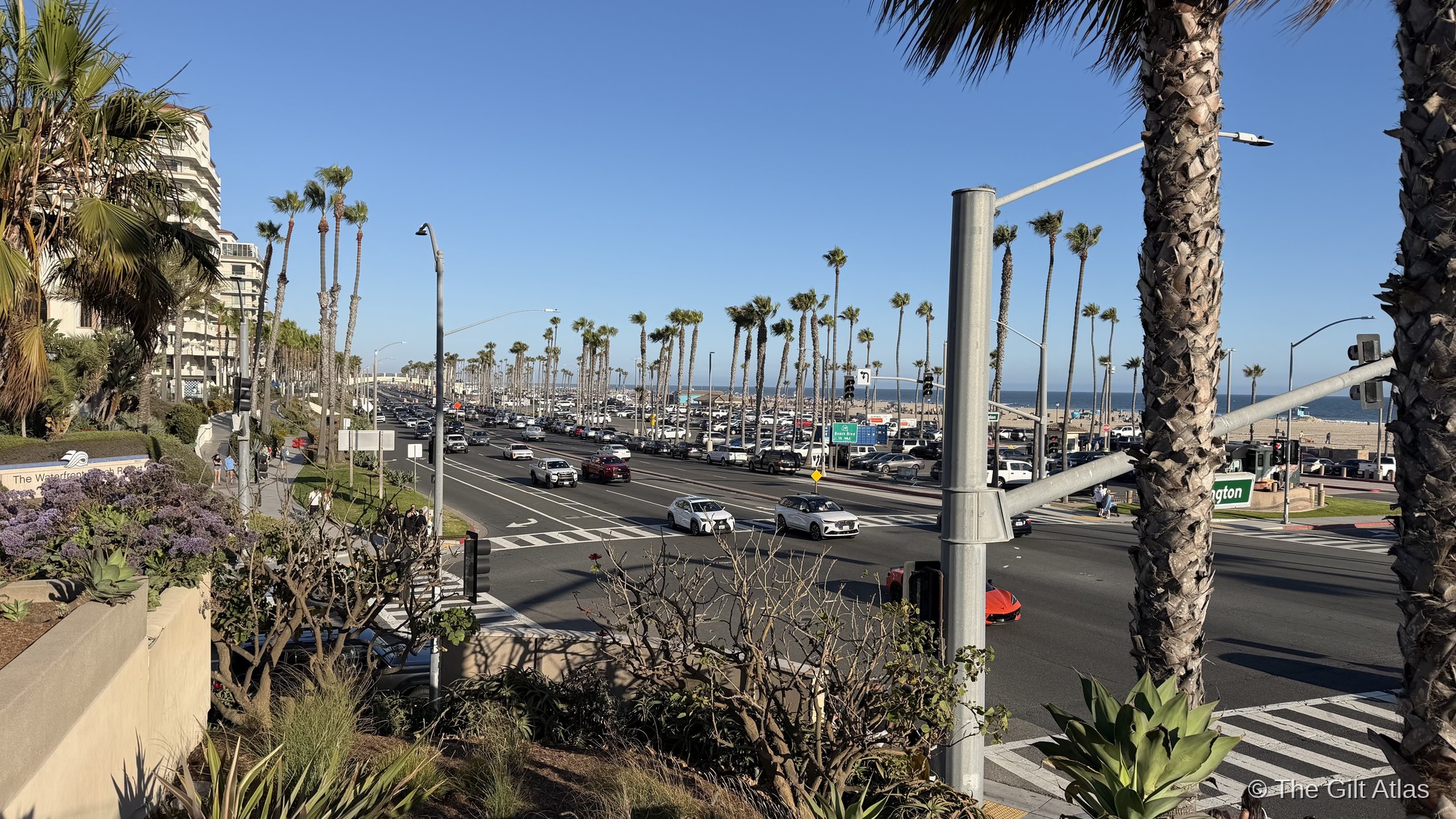 Pacific Coast Highway looking toward Huntington Beach — palm trees, the Pacific, and the pier in the distance