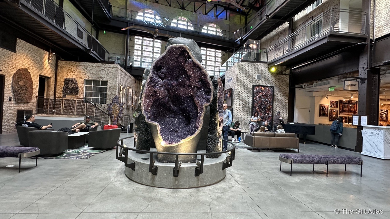 The giant amethyst geode at the center of the Plant Riverside District lobby — a massive purple crystal formation on a steel plinth surrounded by seating