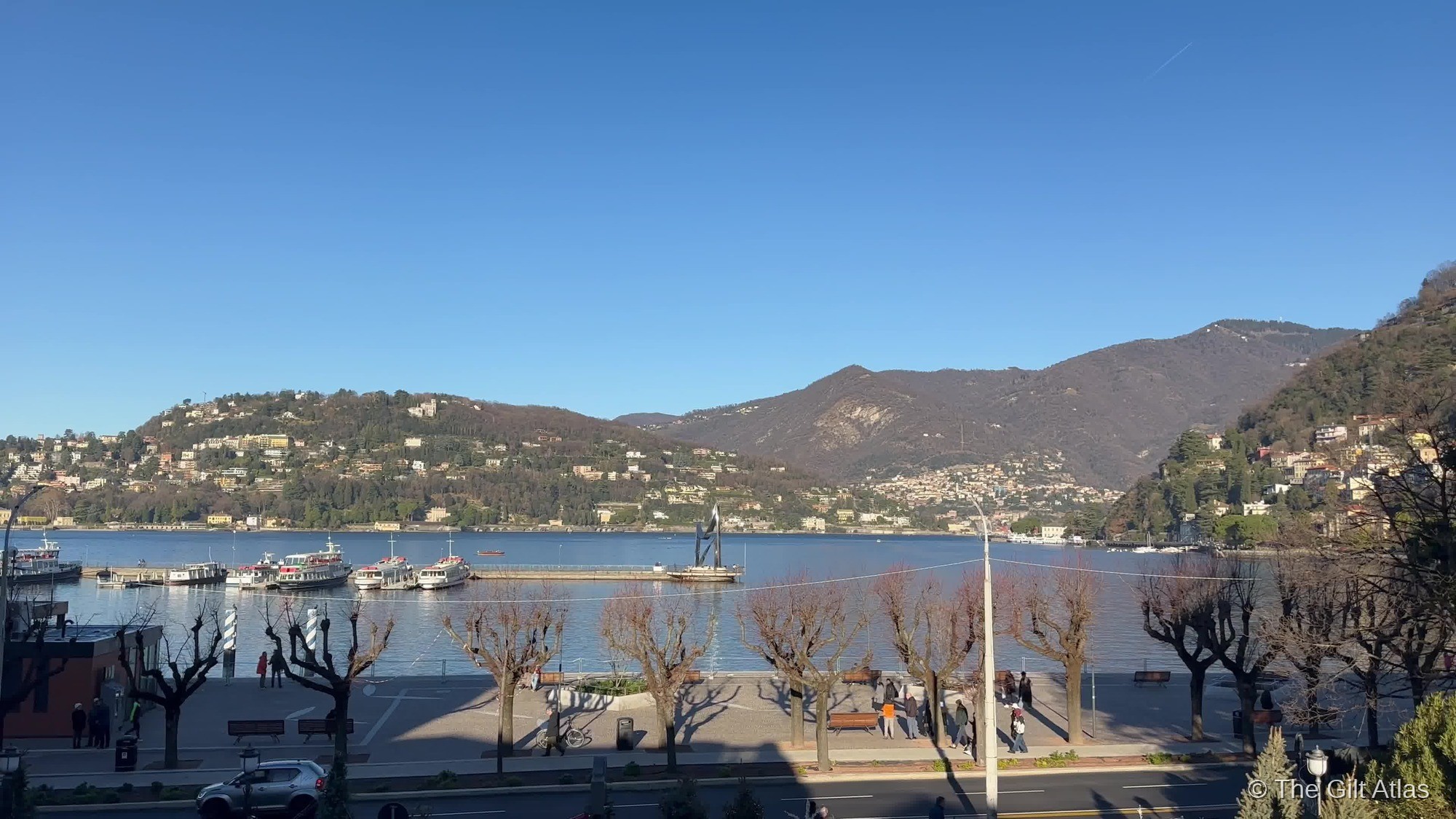 Lake Como from the Hotel Terminus waterfront — the promenade, ferry pier, and Alps beyond