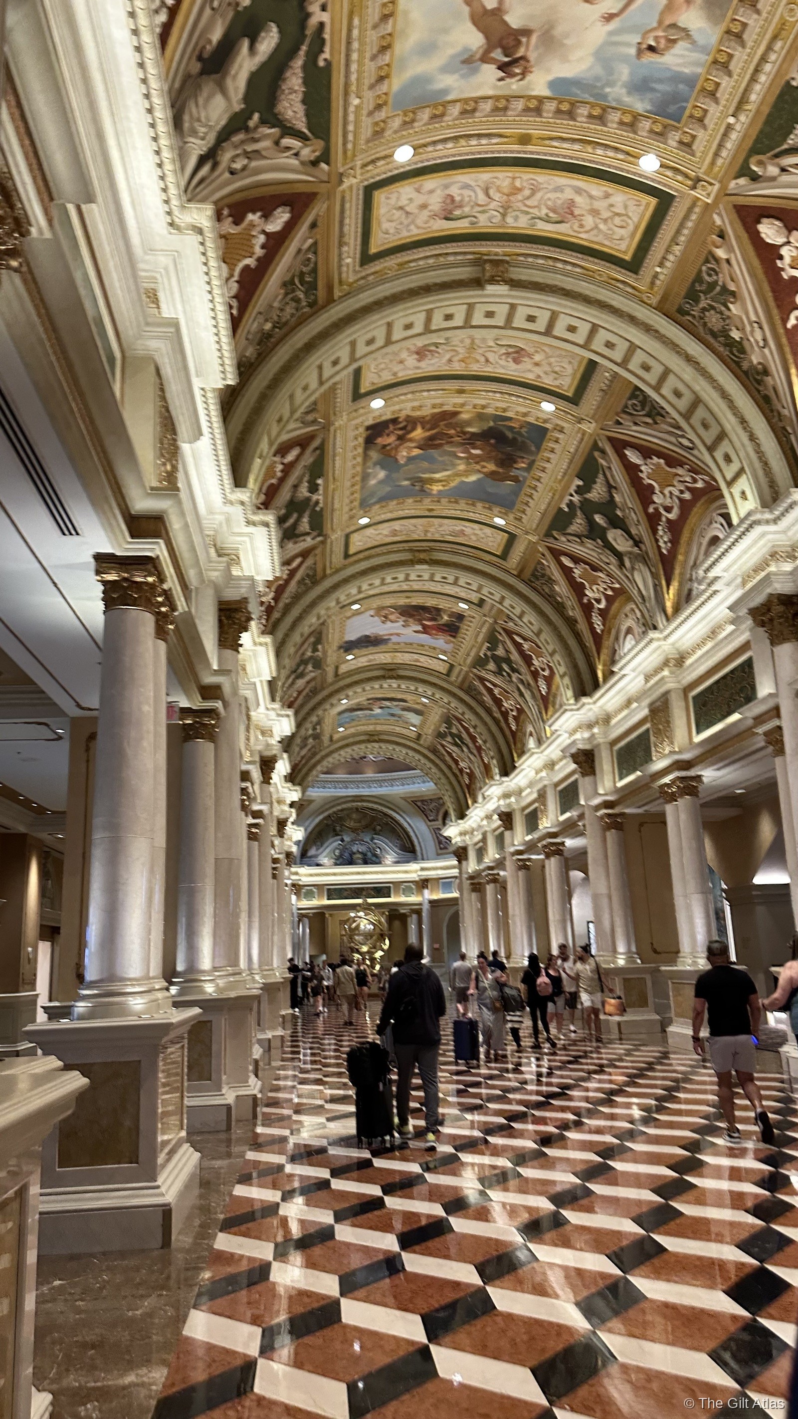 The Venetian's entrance hall — vaulted ceiling with Renaissance frescoes, marble diamond-pattern floors, and colonnades