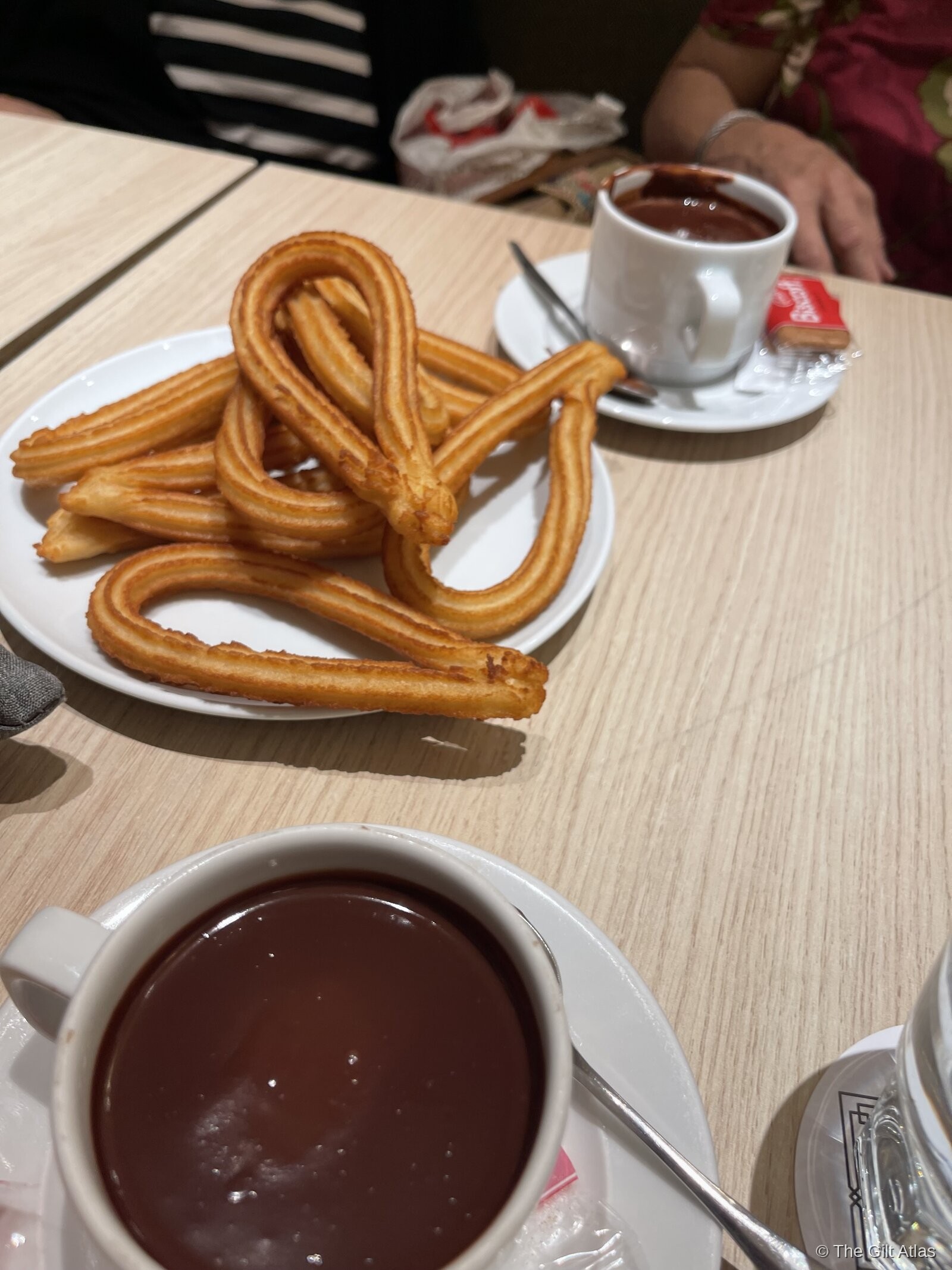 A plate of fresh churros with a large cup of thick hot chocolate for dipping, a classic Madrid chocolate con churros