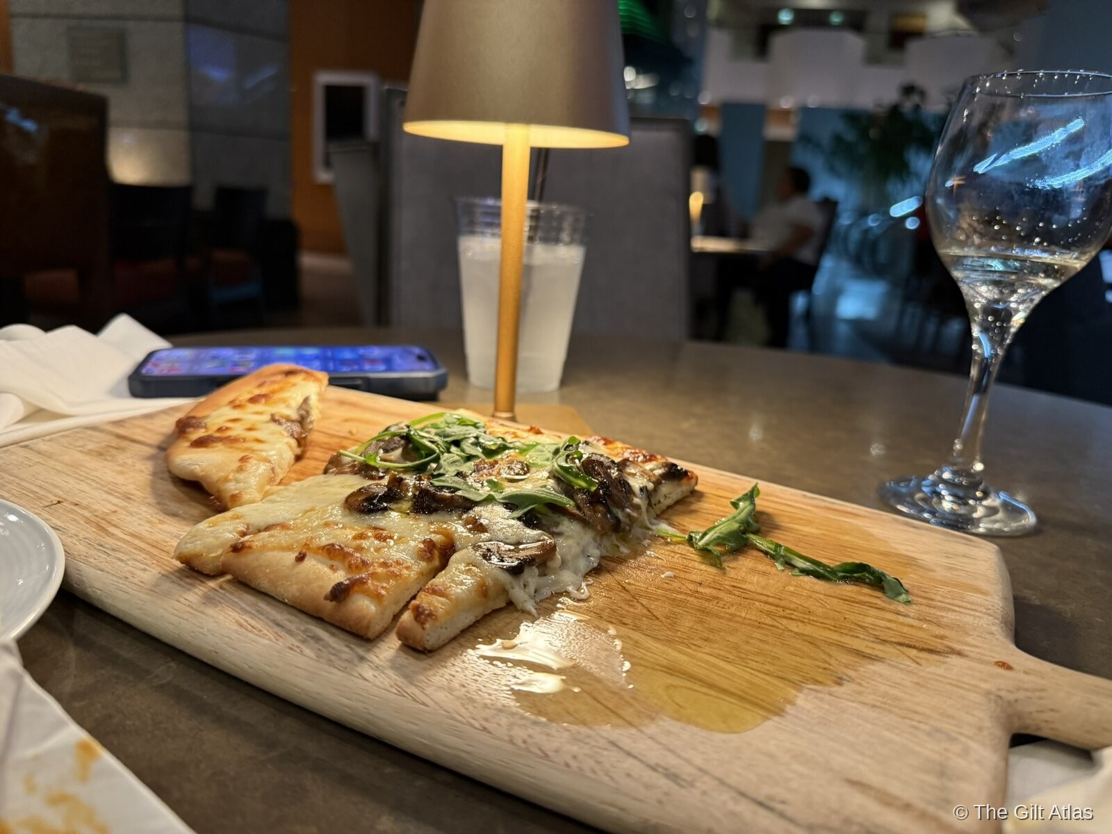 Mushroom and arugula flatbread on a wooden board at the Westin San Diego Bayview bar, with a glass of white wine — evening service